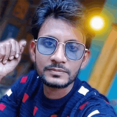 a man with a beard and sunglasses is taking a selfie with his hand in his fist .