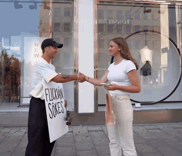 a woman shakes hands with a man holding a sign that says flockman sokes