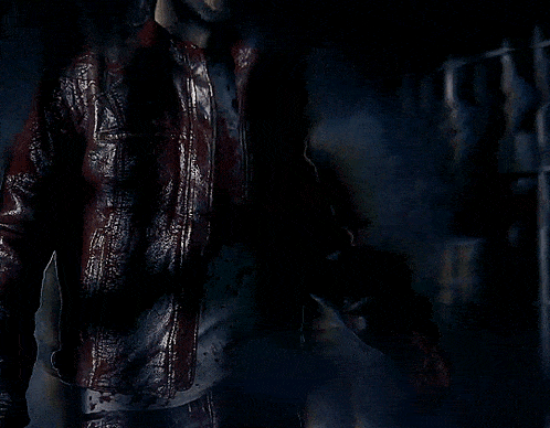 a man with blood on his face is holding a gun in a dark room