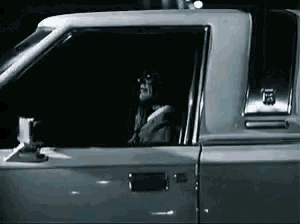 a man is sitting in a car with his head out the window .
