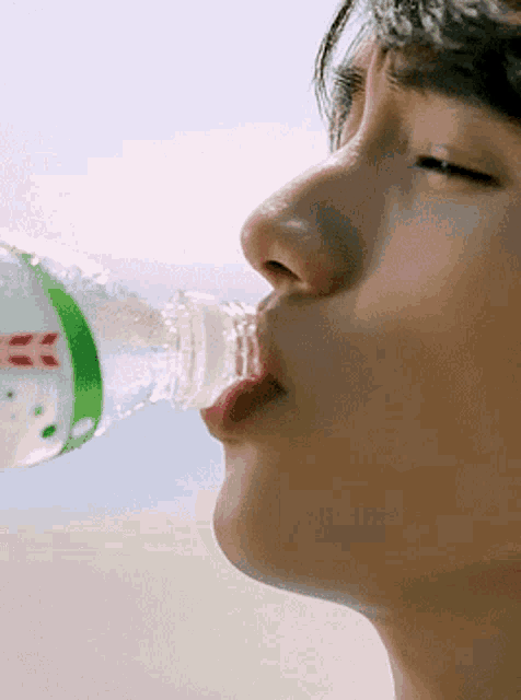 a close up of a person drinking from a bottle