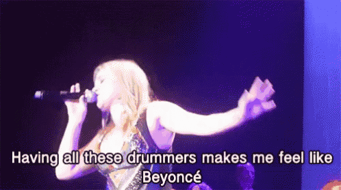 a woman is singing into a microphone with the words having all these drummers makes me feel like beyonce