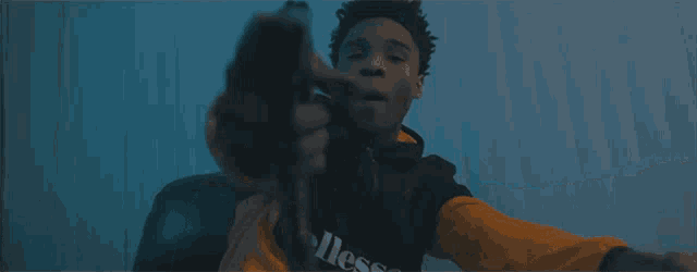 a man in an ellesse sweatshirt holds a gun
