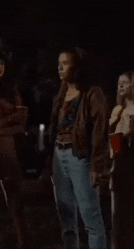 a woman in a brown jacket is dancing in a dark room
