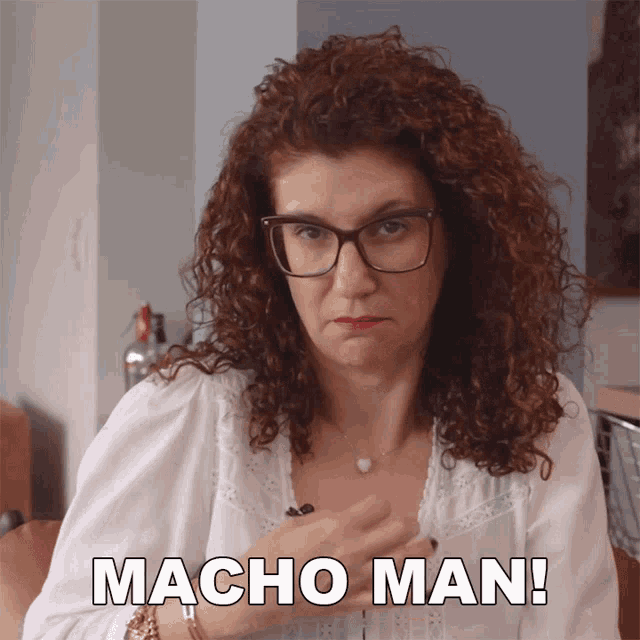 a woman with curly hair and glasses says macho man on the screen