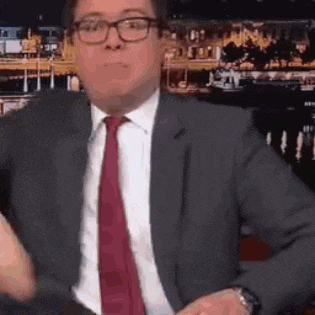 a man in a suit and tie is making a funny face while wearing glasses .