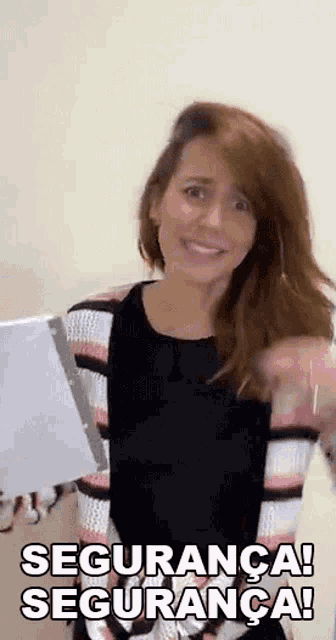 a woman in a striped sweater is holding a piece of paper and smiling while saying segurança ! segurança !