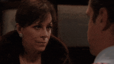 a man in a striped shirt and pink suspenders looks at a woman