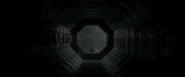 a person is looking out of a hole in a tunnel .