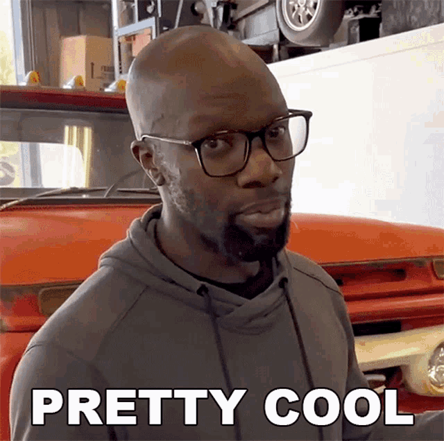 a bald man wearing glasses and a grey hoodie says pretty cool