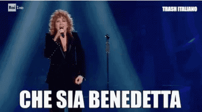 a woman singing into a microphone with the words che sia benedetta on the screen
