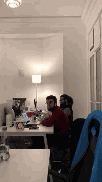 a man sits at a desk with a laptop and a cup of coffee