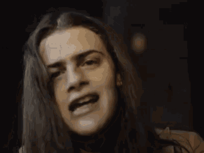 a man with long hair is making a funny face and the word dreams is behind him .