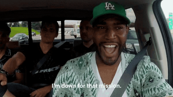 a man wearing a la hat is sitting in the back of a car