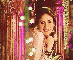 a woman is smiling while standing in front of a mirror with lights behind her .