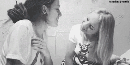 two women are sitting next to each other and looking at each other in a black and white photo .