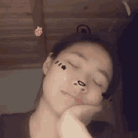 a woman with a tattoo on her face is sleeping with her eyes closed and her hand on her face .