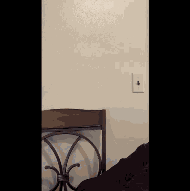 a light switch on a white wall next to a bed