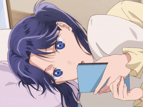 a girl with blue eyes is laying on a bed holding a blue book