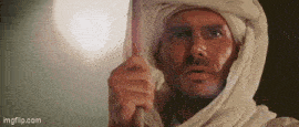a man wearing a white turban is holding a stick in his hand .