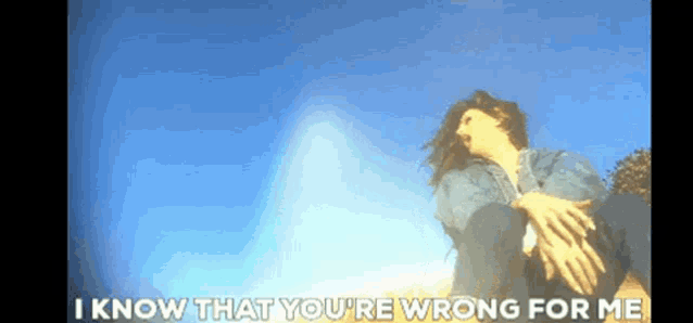 a woman is sitting on the ground with the words " i know that you 're wrong for me " below her