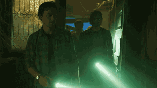two men in a dark room holding a flashlight