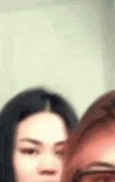 a blurry picture of two women standing next to each other and looking at the camera .
