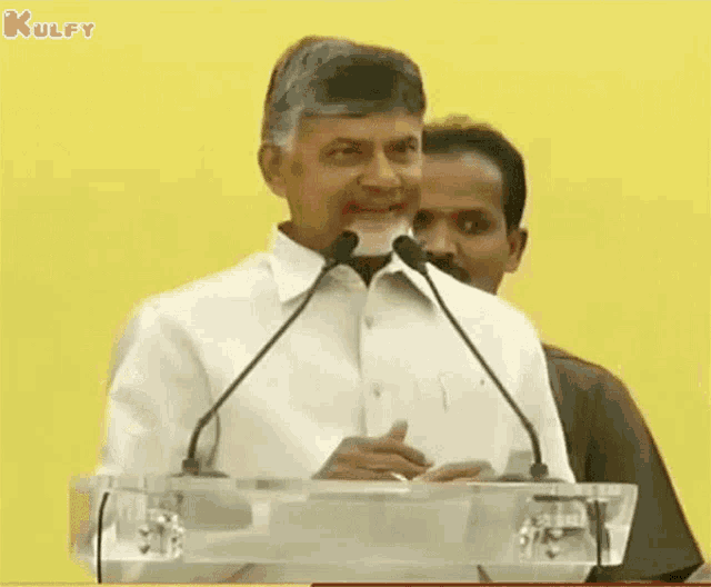 a man is giving an ok sign while speaking into microphones