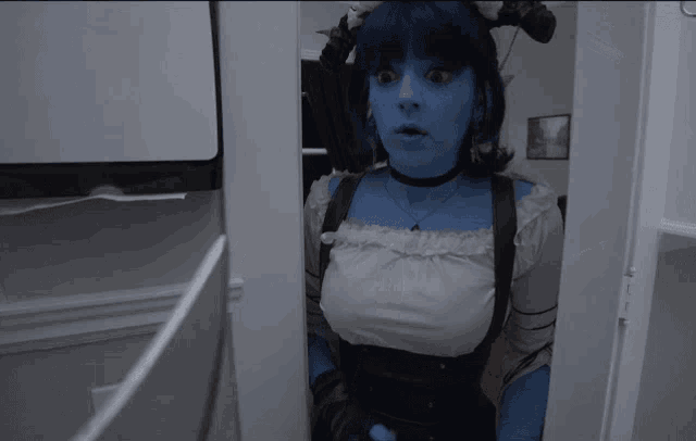 a woman with blue paint on her face is standing in a room