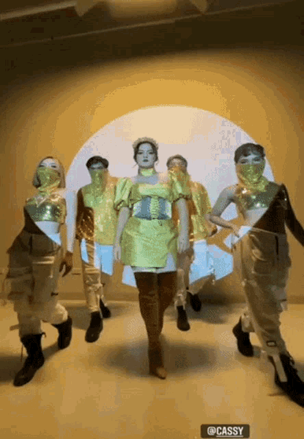 a woman in a yellow dress stands in front of a group of dancers