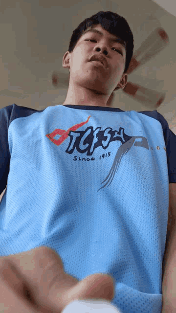 a young man wearing a blue shirt that says tgpa since 1918