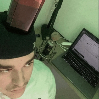 a man wearing a hat with the letter d on it stands in front of a laptop