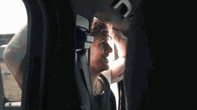a man in a car with a tattoo on his arm looks out the window