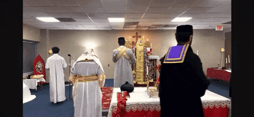 a group of priests are standing in a room with an exit sign