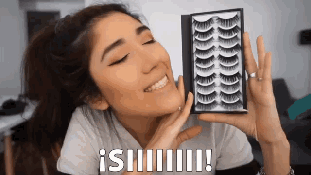 a woman is holding a box of fake eyelashes and smiling with a caption that says ¡ siiiii !!!