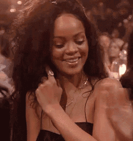 a woman in a black dress is smiling while sitting in a crowd of people .