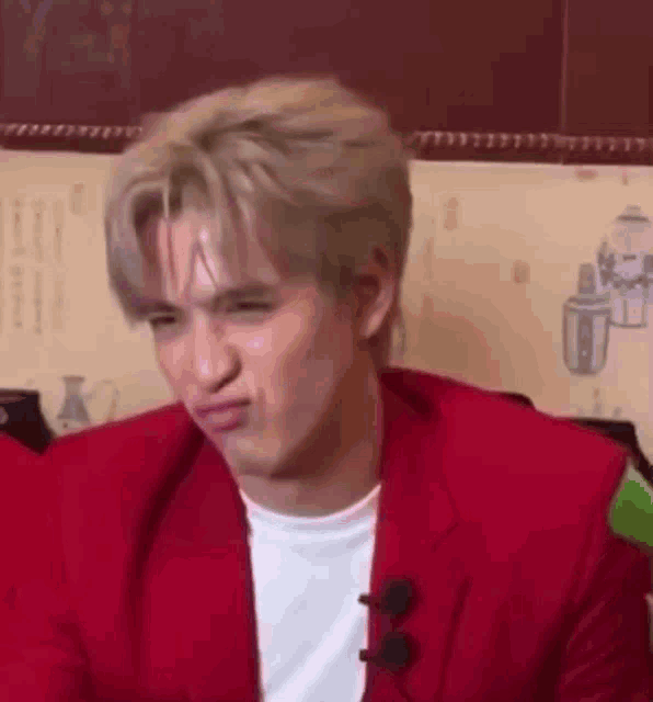 a man in a red suit is making a funny face while sitting at a table .
