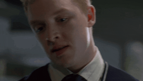 a close up of a man 's face with a white shirt and tie