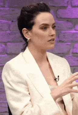 a woman in a white jacket with a microphone on her neck