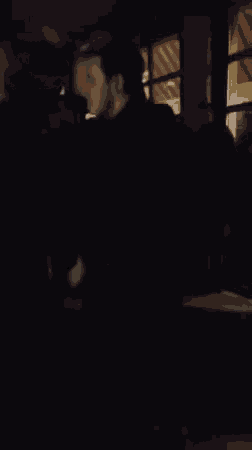 two men are hugging each other in a dark room with a window in the background