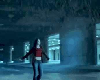 a woman in a red crop top is walking in a dark hallway