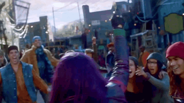 a woman with purple hair is dancing in a crowd of people in a city .
