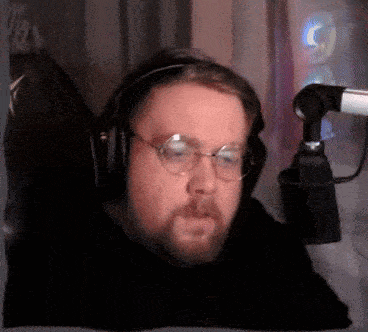 a man with a beard and glasses is wearing headphones and a microphone .