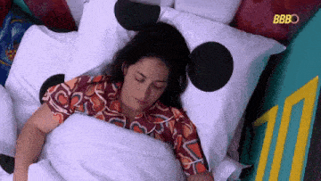 a woman is sleeping in a bed with polka dot pillows and a blanket .