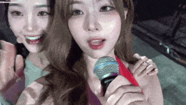 a woman is holding a microphone next to another woman