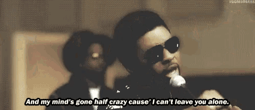 a man wearing sunglasses is singing into a microphone while another man watches .