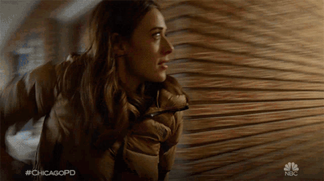 a woman in a brown jacket is standing in front of a wooden wall with the hashtag #chicagopd