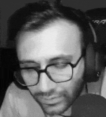 a man with glasses and headphones is talking into a microphone .