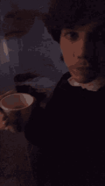 a man in a black shirt is holding a cup of coffee