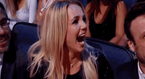 a woman is laughing in a crowd of people while sitting in a stadium .